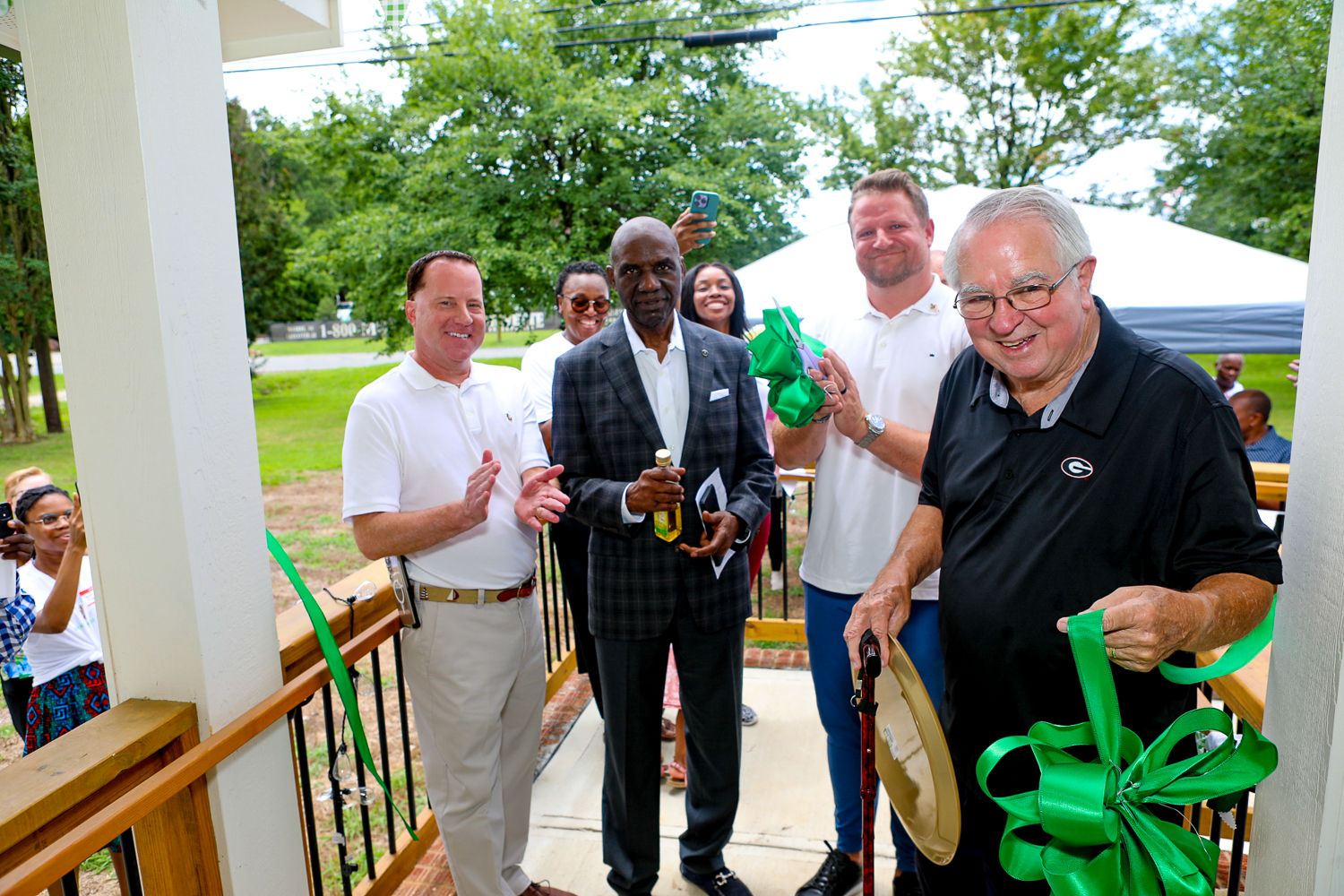 Guests holding a ribbon and ceremonial scissors outside Gracious Senior Living